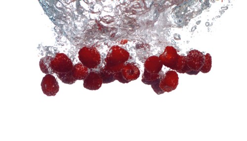iStock Video Footage - Raspberries splashing into water, slow motion